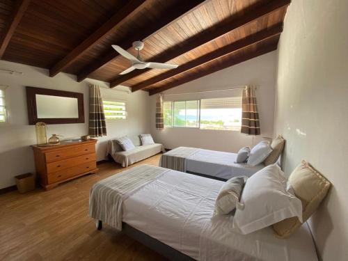 a bedroom with two beds and a ceiling fan at Notre Vie Là in Le Robert