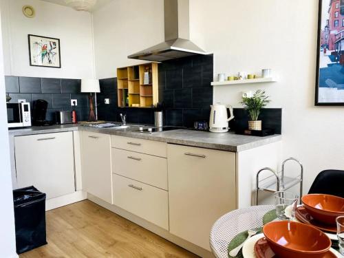 a kitchen with white cabinets and a table with a tableablish at Le Cassiopée - Vue incroyable surplombant Rennes in Rennes