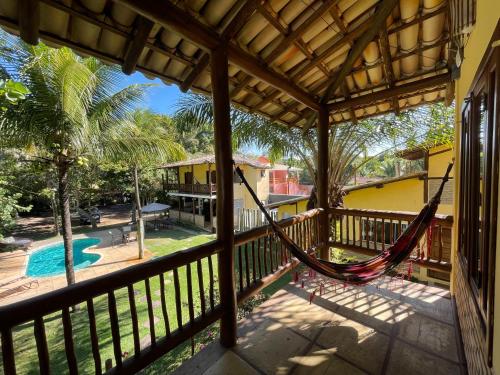 a hammock on the porch of a house with a pool at Maui Suítes e Chalés in Arraial d'Ajuda