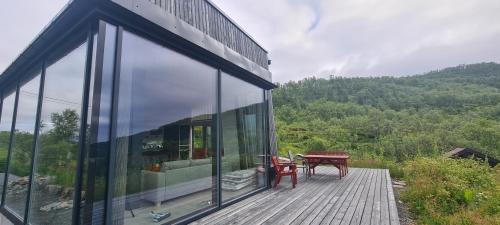 a glass building with a picnic table on a deck at Senjavista, near nature, sea and mighty mountains in Skaland