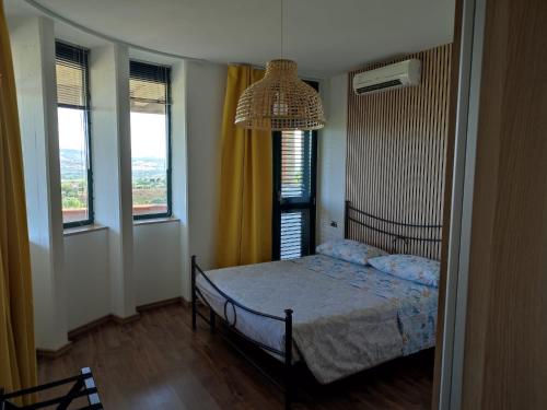 a bedroom with a bed and a chandelier and two windows at Villa Giuseppe in Roseto degli Abruzzi