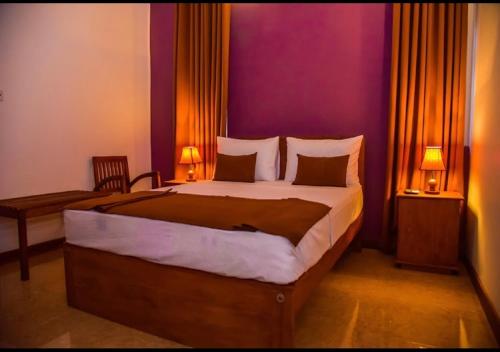 - une chambre avec un grand lit et un mur pourpre dans l'établissement Ace Boutique Airport, à Katunayake