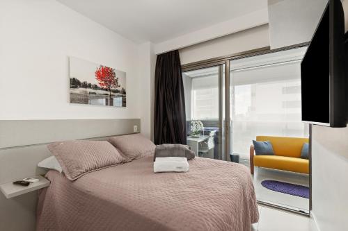 a bedroom with a bed and a tv and a chair at Magníficos Ap Luxo - 43mts e 63mts, 1 ou 2 Qtos in Sao Paulo