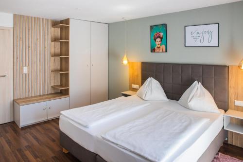 a bedroom with a large white bed and a shelf at Pension Waldesruh in Bad Ischl