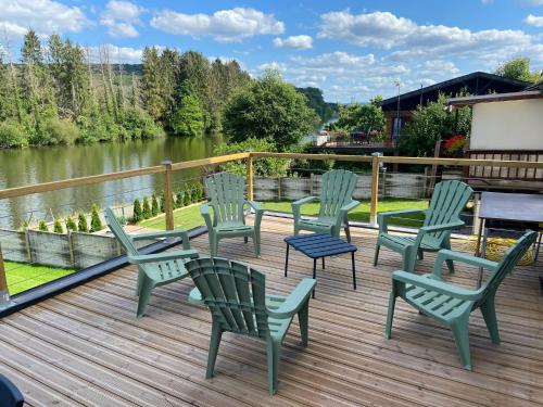 un groupe de chaises assises sur une terrasse à côté d'une rivière dans l'établissement La Villa Wellness, à Hastière-par-delà
