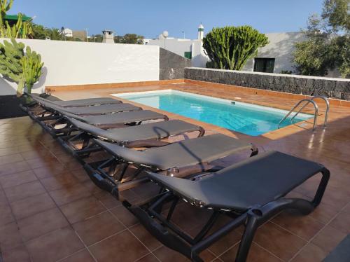 a group of lounge chairs next to a swimming pool at VILLA MARTINA in Playa Blanca
