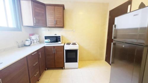 a small kitchen with a refrigerator and a microwave at Hotel Leaders Plaza Salmiya in Kuwait