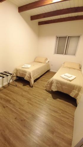 two beds in a room with wooden floors at HOME TRES ESPERANZA a 2 cuadras de peatonal in Resistencia