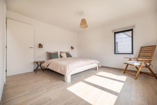 a white bedroom with a bed and a chair at Villa Dianga (De Haan) in De Haan