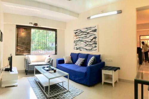 un soggiorno con divano blu e tavolo di White Rose, at Carter Road by Connekt Homes a Mumbai