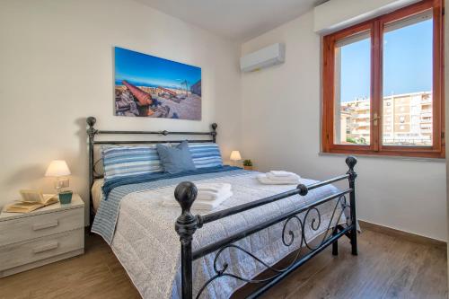 Un dormitorio con una cama y una ventana grande. en Pufferfish Apartment with private terrace, en Alghero