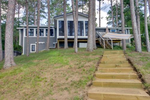 a house in the woods with stairs leading up to it at Lakefront Nevis Cabin Escape with Hot Tub! in Nevis