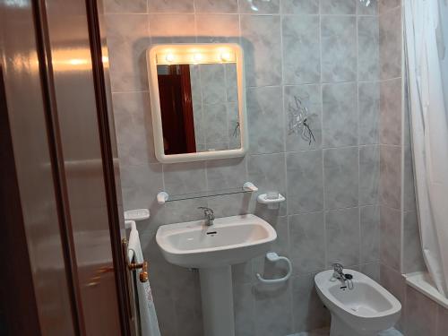 a bathroom with a sink and a mirror and a toilet at Apartamento RUAL in Sanxenxo