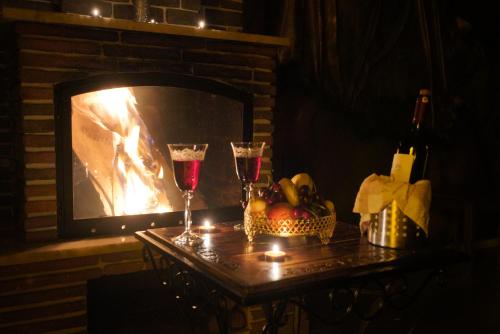 a table with two glasses of wine and a fireplace at Moonlight of Cappadocia in Uchisar