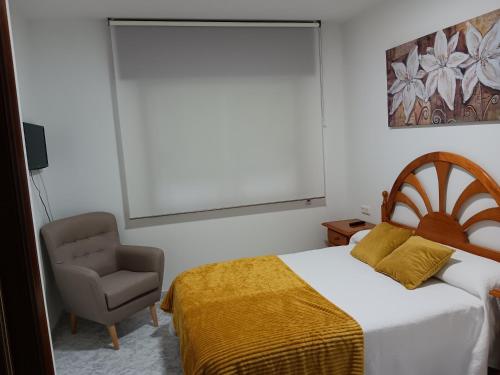 a bedroom with a bed and a chair at Apartamento RUAL in Sanxenxo