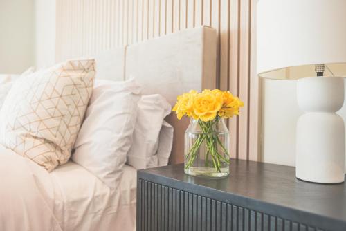 a vase of yellow flowers on a table next to a couch at NOVU Apartments Liverpool Waterfront in Liverpool