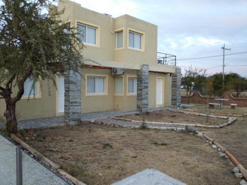 Una casa amarilla con un árbol delante. en Anan en Cortaderas