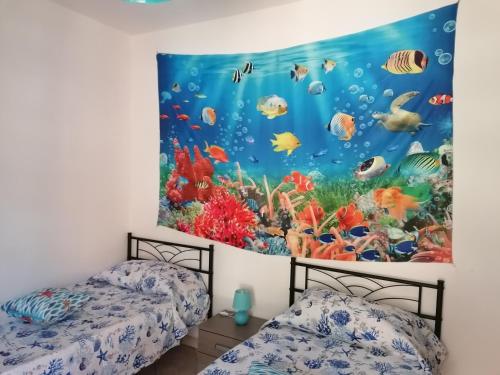 2 letti in una camera con un murale ad acquario sulla parete di La Stella Marina a Bari Sardo