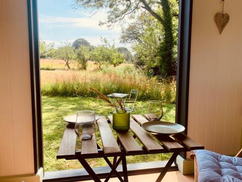 a wooden table sitting in front of a window at Apple Orchard Shepherd Huts in Staple Cross