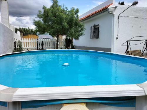 una grande piscina blu di fronte a una casa di El Capricho a Benalup-Casas Viejas
