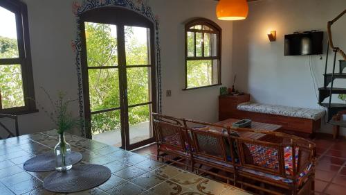sala de estar con mesa y algunas ventanas en Chalé à 300 m da praia Rasa, com horta orgânica, en Búzios