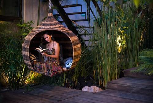 a woman sitting in a wicker swing reading a book at Cuna del Cielo in San Miguel de Allende
