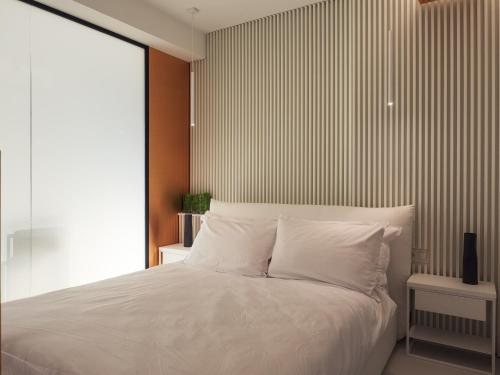een slaapkamer met een wit bed en een gestreepte muur bij Apartament 18 piętro UNIQUE APARTMENTS 4 YOU in Warschau