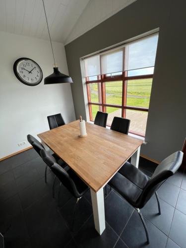 a dining room table with chairs and a clock on the wall at Fíflholt in Hvolsvöllur