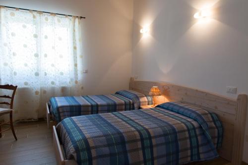 two beds in a small room with a window at B&B Dolomitincanto in Cesiomaggiore