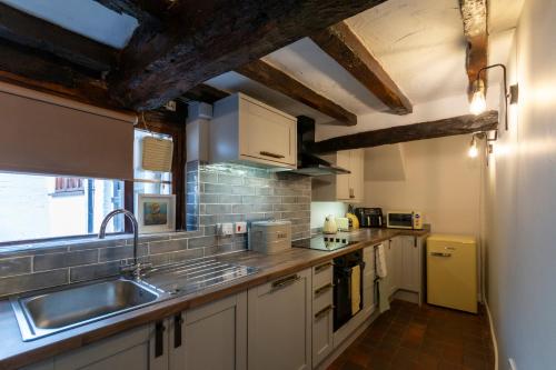 a kitchen with white cabinets and a sink at Bewdley River Cottage - Free private gated parking for 2 cars - River front location in Bewdley