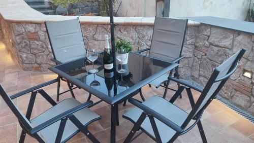una mesa de cristal con 3 sillas y copas de vino en Sa Benedica - Luxury House, en Calatabiano