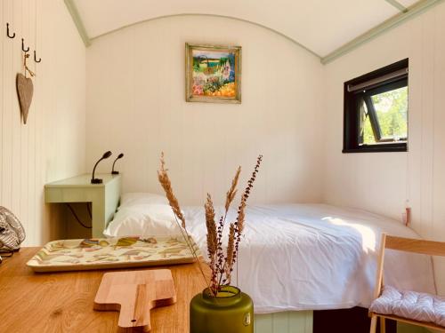 - une chambre avec un lit, une table et un banc dans l'établissement Apple Orchard Shepherd Huts, à Staple Cross
