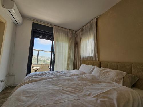a bedroom with a large bed with a large window at פנטהאוז ברמה in Bet Shemesh