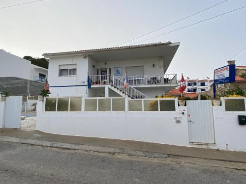 a white house with a white fence at Casa Godinho in São Martinho do Porto