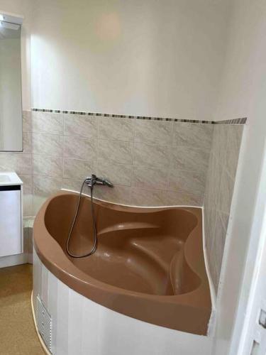 une baignoire marron dans une salle de bain avec un mur carrelé dans l'établissement Le Saint Joseph, à Châlons-en-Champagne