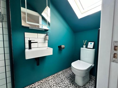 a bathroom with a toilet and a blue wall at 3a Roman View, beautifully appointed apartment in Roundhay, sleeps up to 6, bedrooms with en suite bathrooms, EV charging in Moortown