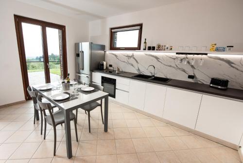 a kitchen with a table with chairs and a refrigerator at Il Casot Private House with Pool in Borgomale