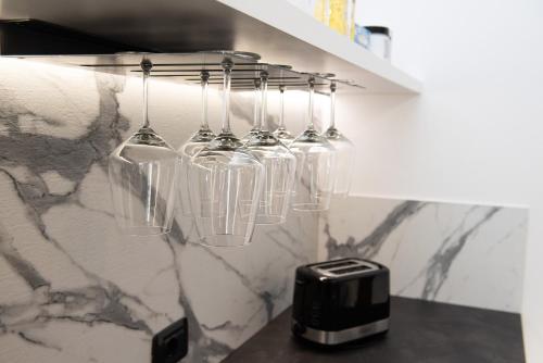 a group of wine glasses hanging from a rack in a kitchen at Il Casot Private House with Pool in Borgomale