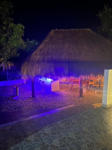 a hut with a table and chairs at night at Villa campestre Casa Blanca Full House in Agua de Dios