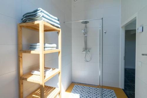 baño con ducha y estante de madera con toallas en Het Betuws Erfje, en Maurik