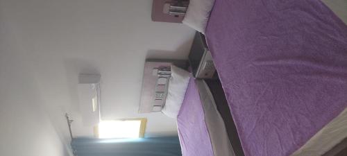 Una cama en una habitación con sábanas moradas. en منتجع ديار السكنى, en Dawwār Abū Maḩrūs