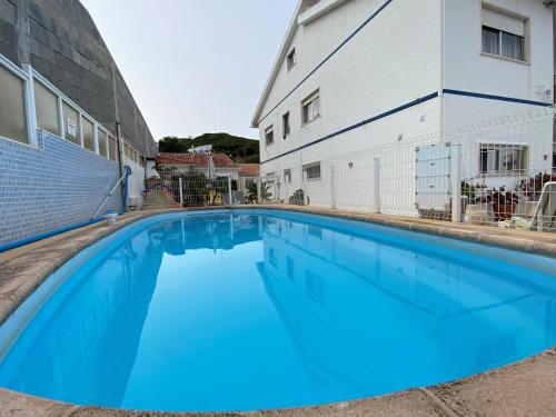 a large blue swimming pool next to a building at Casa Godinho in São Martinho do Porto