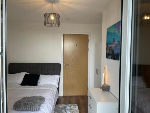 a bedroom with a bed and a wooden door at Luxury 2 Bedroom En-Suite Apartment Balcony Views in Manchester