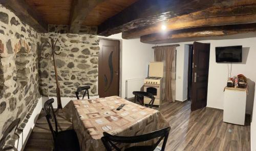 una mesa y sillas en una habitación con una pared de piedra en Casa de sub Salcie en Curtea de Argeş