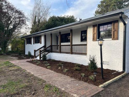 a white brick house with a porch and a street light at Newly renovated rancher with yard and garage! Furnished! in Williamsburg