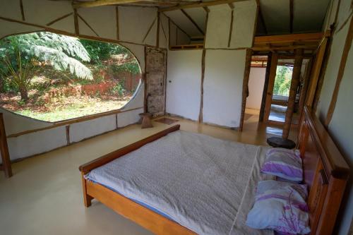 Bett in einem Zimmer mit einem großen Fenster in der Unterkunft Ecolodge Jaguarundi in Cali