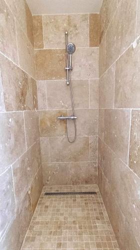 La salle de bains est pourvue d'une douche et de carrelage. dans l'établissement Gîte les Tilleuls, à Gouchaupré