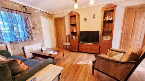 a living room with a couch and a tv at La casita "A de Naval" in Pontevedra