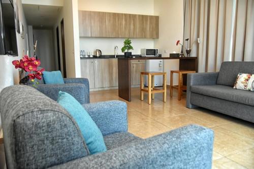 sala de estar con 2 sillas azules y cocina en Byblostar Hotel en Jbeil