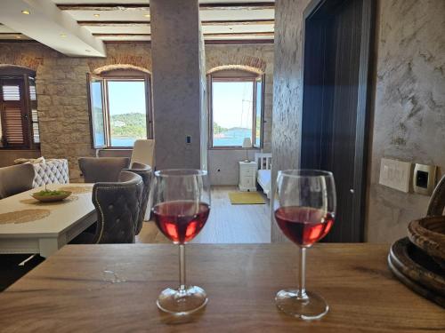 two glasses of red wine sitting on a wooden table at Luxury Seafront Suite Fabri in Vis